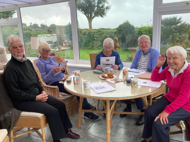 group of five people sitting at table looking at art